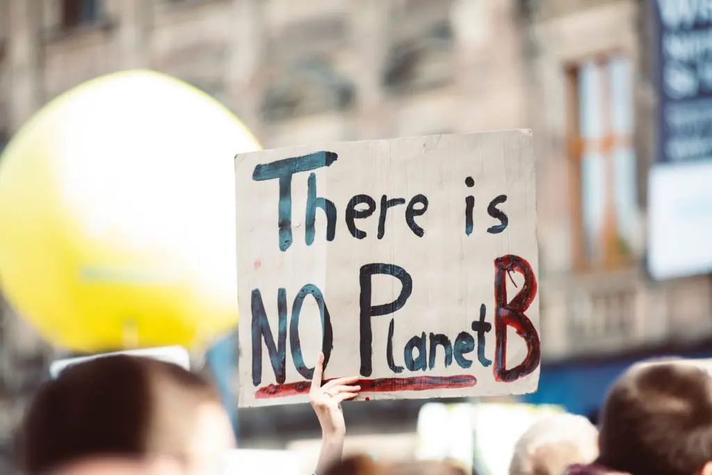 Sign reads "There is no planet B" against blue sky background.
