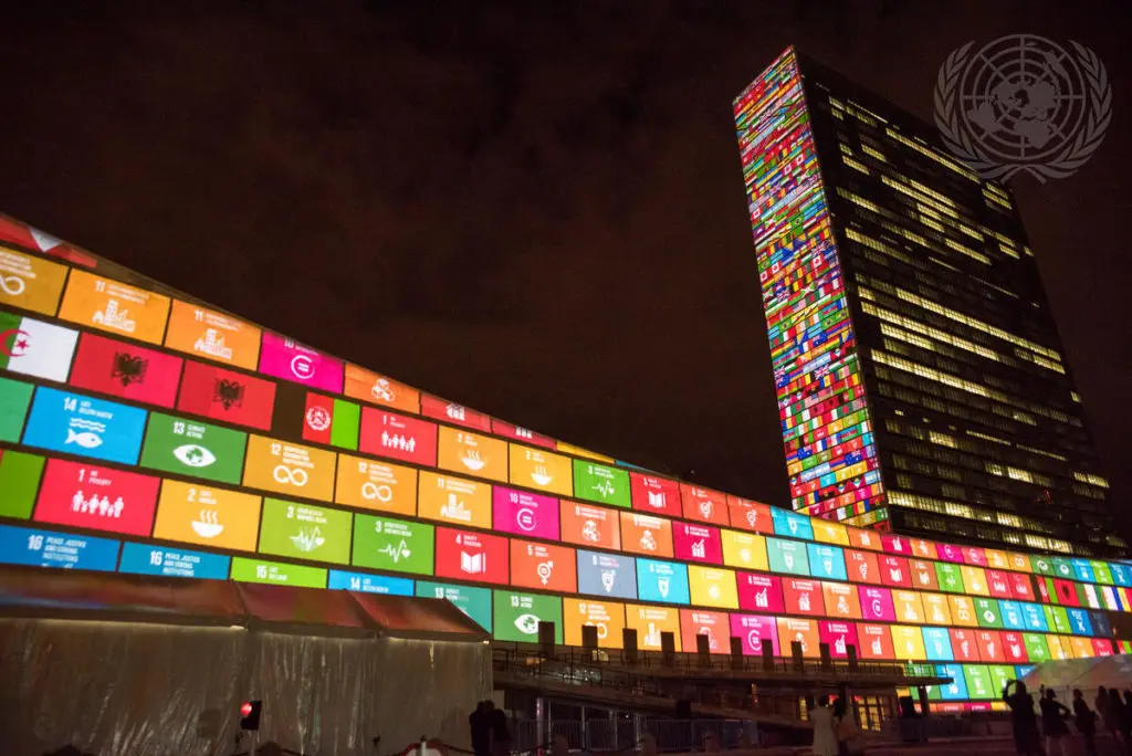 The UN headquarters displays colorful projections of Sustainable Development Goals at night.